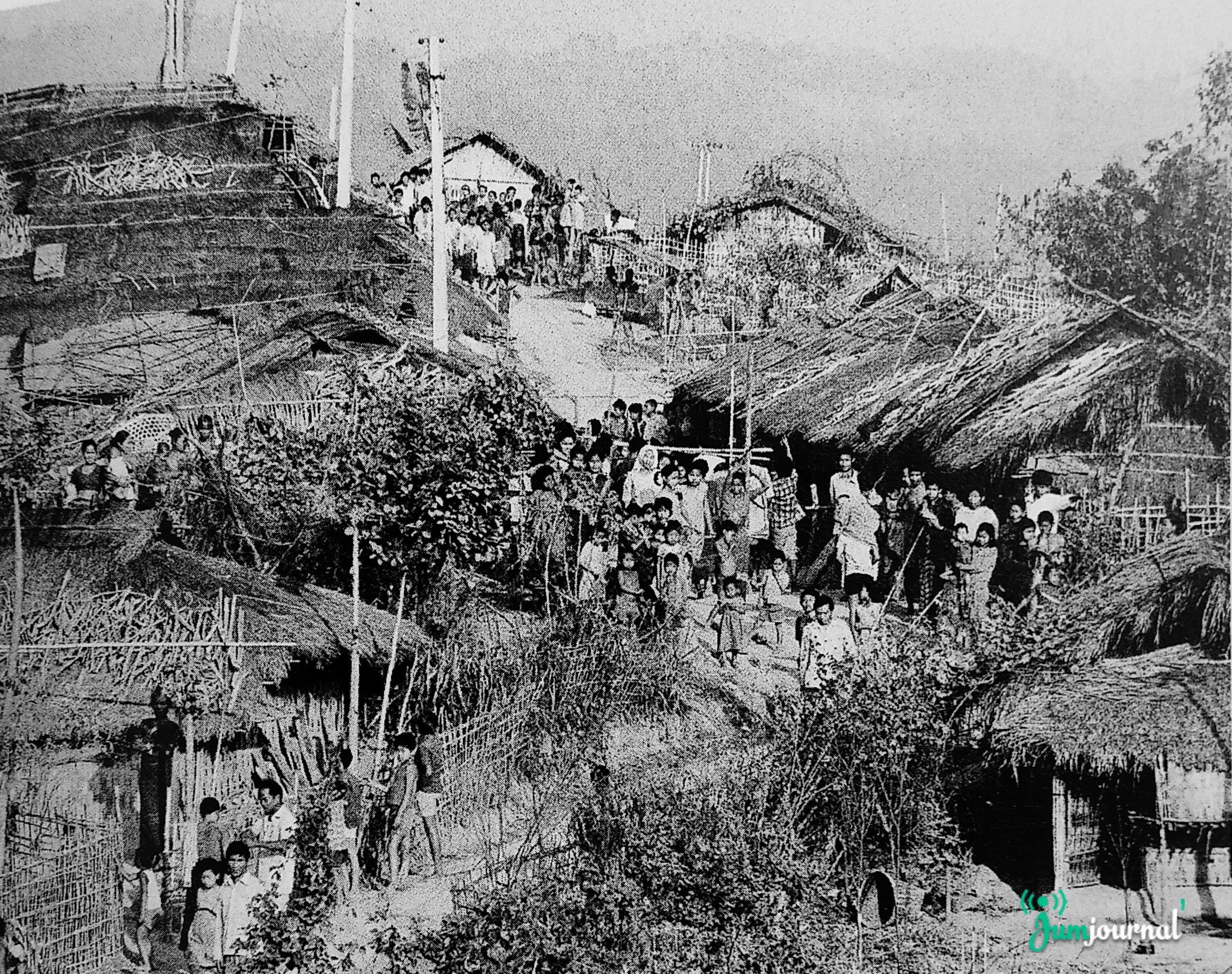 ১৯৯০ সালে ত্রিপুরার পঞ্চরামপাড়া চাকমা শরণার্থী শিবিরে খড়ের চালের সারি সারি ঘর, পাহাড়ি ঢালের পথে দাঁড়িয়ে নারী, পুরুষ ও শিশুদের ভিড়