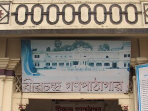 পাঠাগারের সামনের দেয়ালে বাংলায় লেখা “বীরচন্দ্র গণপাঠাগার”, উপরে সারি সারি গোলাকার নকশা