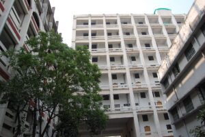 গাছের আড়াল থেকে দেখা বহুতল আদালত ভবন, সারি সারি জানালা ও বারান্দা