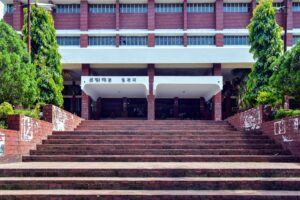 চট্টগ্রাম বিশ্ববিদ্যালয়ের লাল ইটের গ্রন্থাগার ভবন — চওড়া সিঁড়ির ওপরে প্রবেশপথে বাংলায় লেখা 'গ্রন্থাগার ভবন', দুপাশে সবুজ গাছ