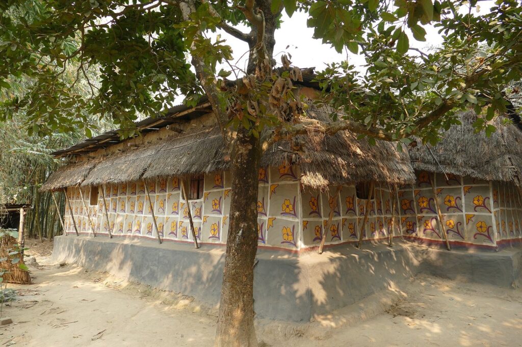 দিনাজপুরের একটি সাঁওতাল গ্রামে খড়ের চালের মাটির ঘর, দেয়ালে সাদা খোপে রঙিন ফুলের নকশা আঁকা